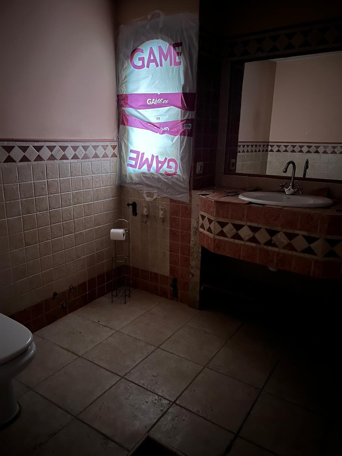 Baño antes de la reforma con alicatado antiguo de tonos terrosos y encimera de obra