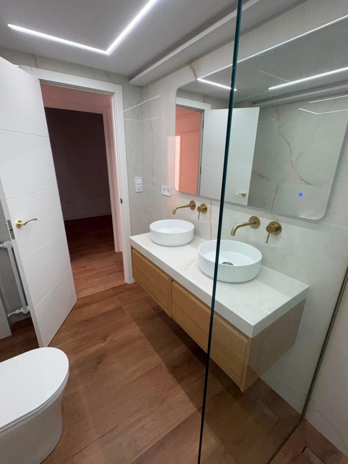 Baño reformado con doble lavabo y mobiliario de líneas limpias