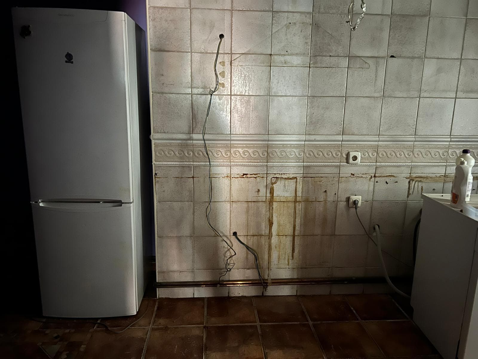 Cocina antes de la reforma, con azulejos antiguos manchados y cables a la vista